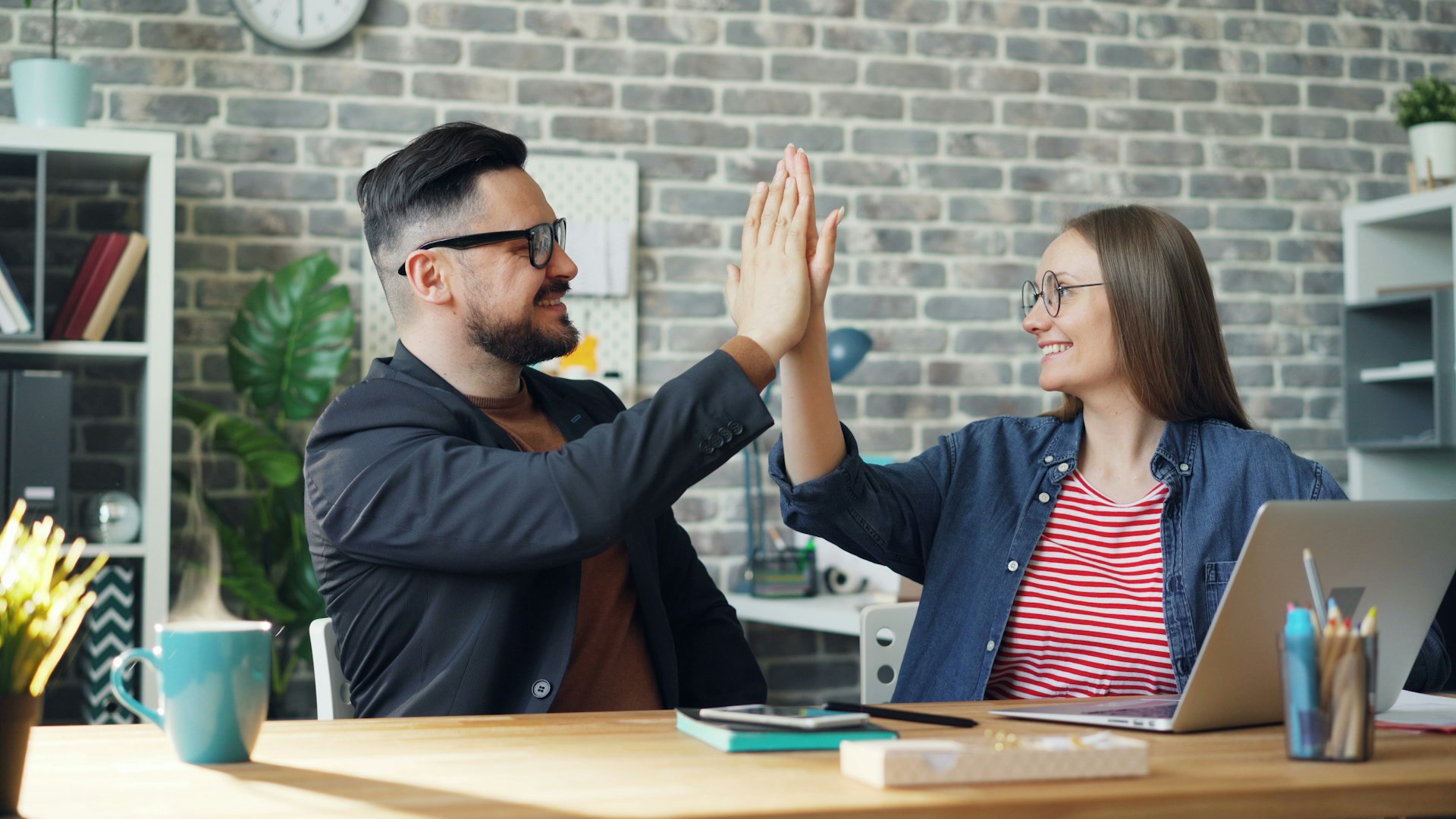 a man and a woman sitting at a table high fiving each other